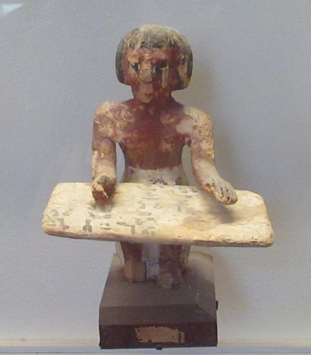 Sculpture of a scribe working with scribal tools.