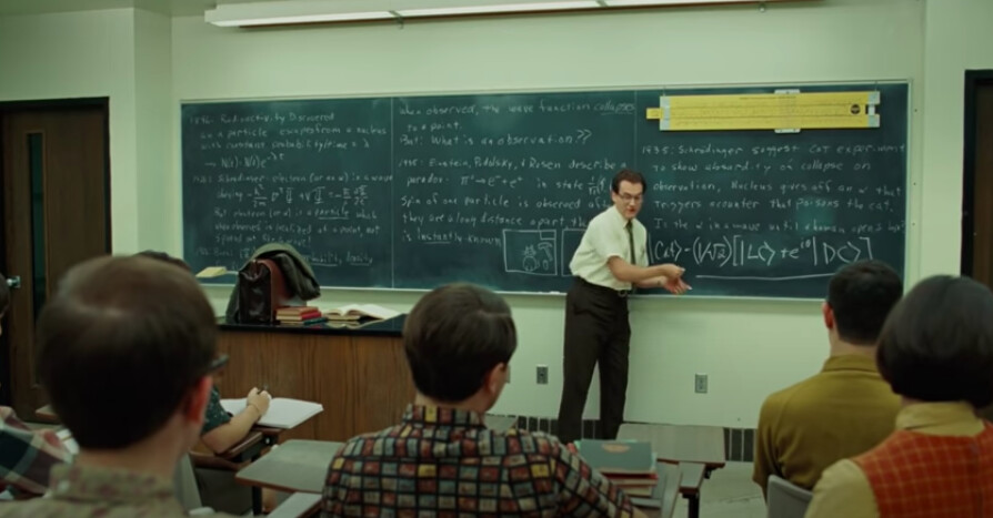 Screenshot showing a demonstration slide rule mounted on the blackboard from A Serious Man (2009).