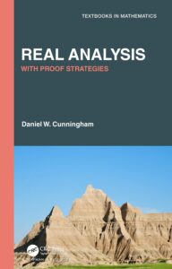 Book cover of "Real Analysis with Proof Strategies" by Daniel W. Cunningham, part of the Textbooks in Mathematics series. The top half features a dark teal background with bold white and coral-colored text, while the bottom half shows a scenic photograph of rocky, mountainous terrain under a clear blue sky. Published by CRC Press, a Chapman & Hall Book.
